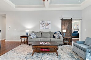 A living room with a grey sofa, a coffee table, and a world map artwork on the wall. - Kentucky Getaway/Hot Tub (Georgetown)