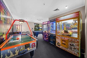 A room with a pool table, claw machines, and a colorful wall. - Coastal Outlook - Caloundra Poolside Apartment (Caloundra Region)