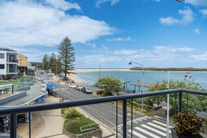 A coastal road with a pedestrian crossing, a beach, and a view of the sea. - Coastal Outlook - Caloundra Poolside Apartment (Caloundra Region)