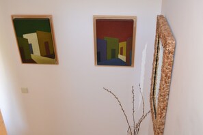 Two framed artworks on a wall, a woven basket, and a bare branch. - Bahía Meloneras Villas Bahmel01 (San Bartolomé de Tirajana)