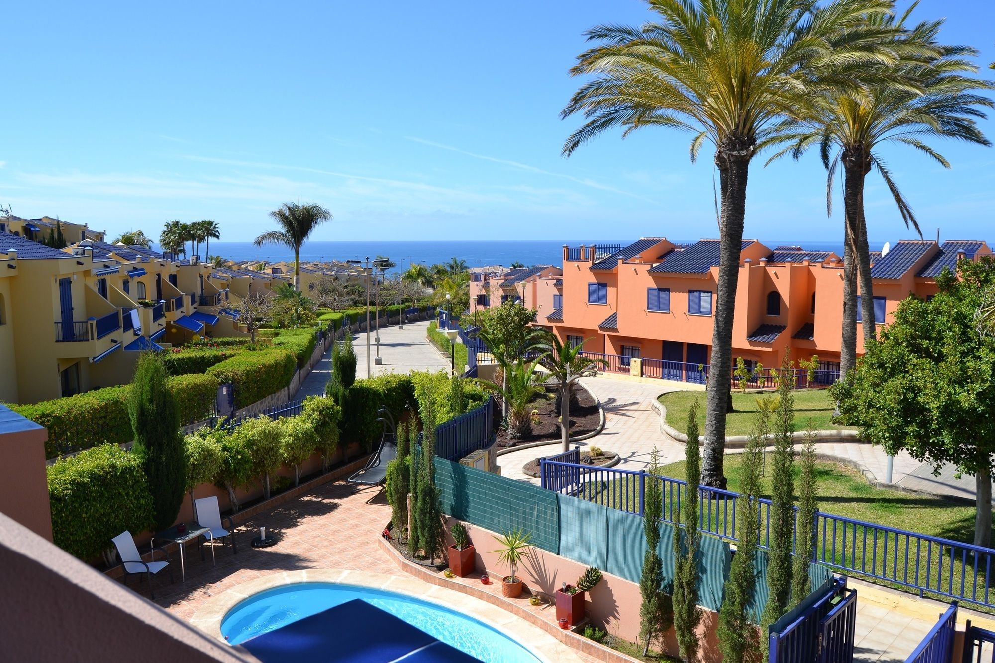 A resort with a swimming pool, palm trees, and a view of the ocean.