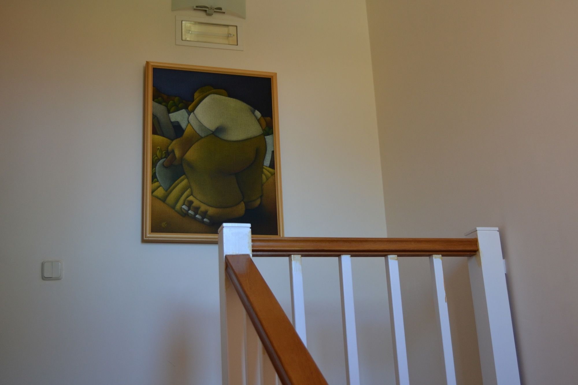 A staircase with a white railing and a painting on the wall above.