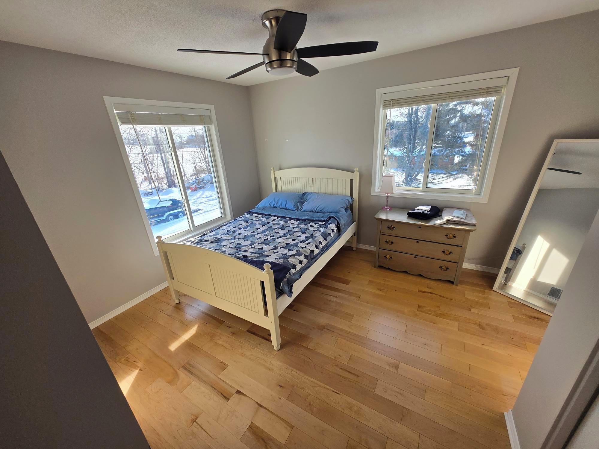 Een slaapkamer met een bed, een dressoir en een plafondventilator.