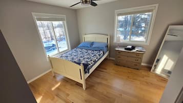Een slaapkamer met een bed, een dressoir en een plafondventilator.