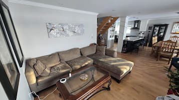 Ein Wohnzimmer mit einem Ecksofa, einem Glastisch und einem Bild an der Wand.