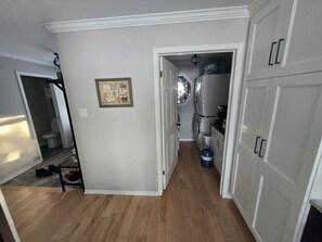 A narrow hallway with a wooden floor, a white door, and a small window.