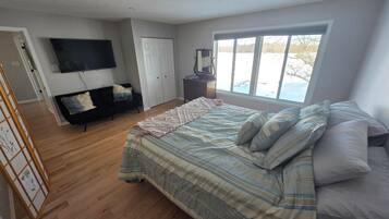 A bedroom with a large bed, a TV, a dresser, and a window with a view.