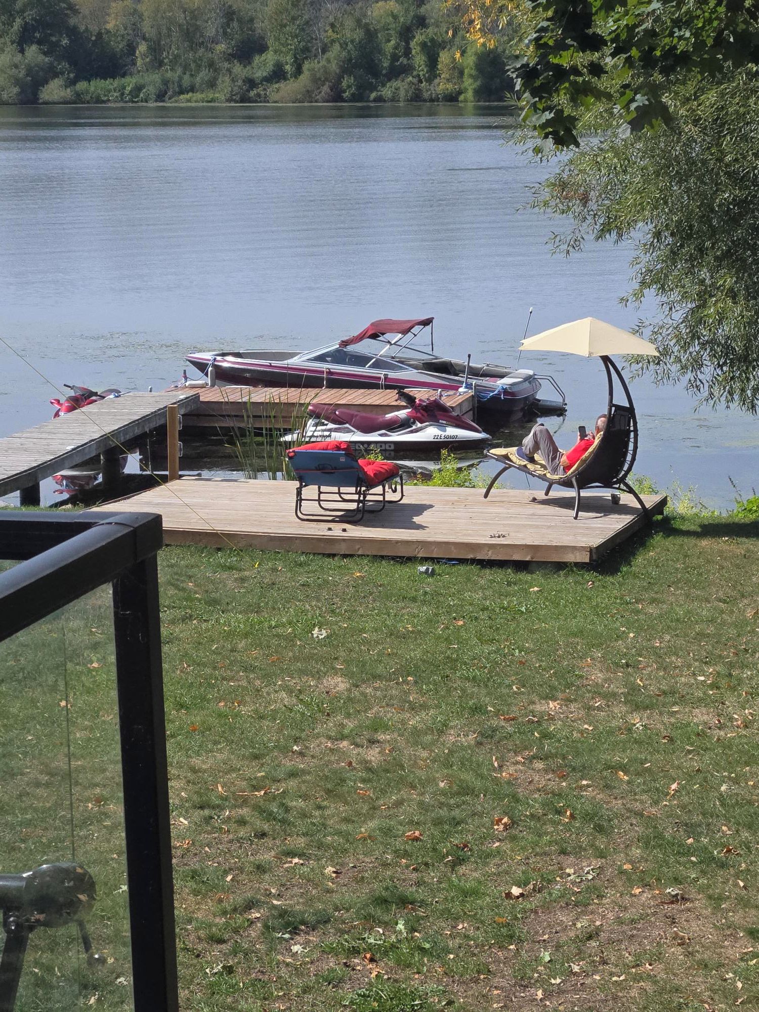 Una terrassa al costat del llac amb un moll per a embarcacions, gandules i una tanca.
