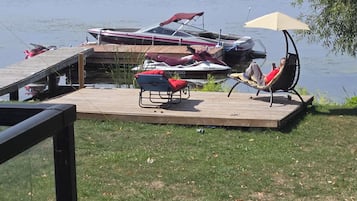 Una terrassa al costat del llac amb un moll per a embarcacions, gandules i una tanca.