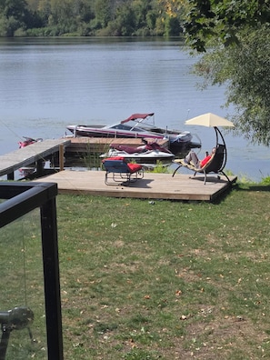 A lakeside deck with a boat dock, lounge chairs, and a canopy.