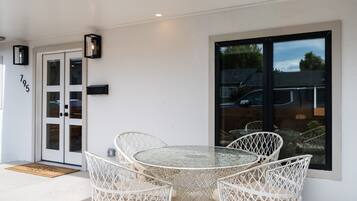A patio with a round table and four wicker chairs, a door with glass panels, and a mailbox on the wall.