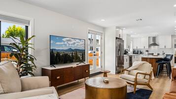 A modern living room with a flat-screen TV, comfortable seating, and a view of the outdoors.