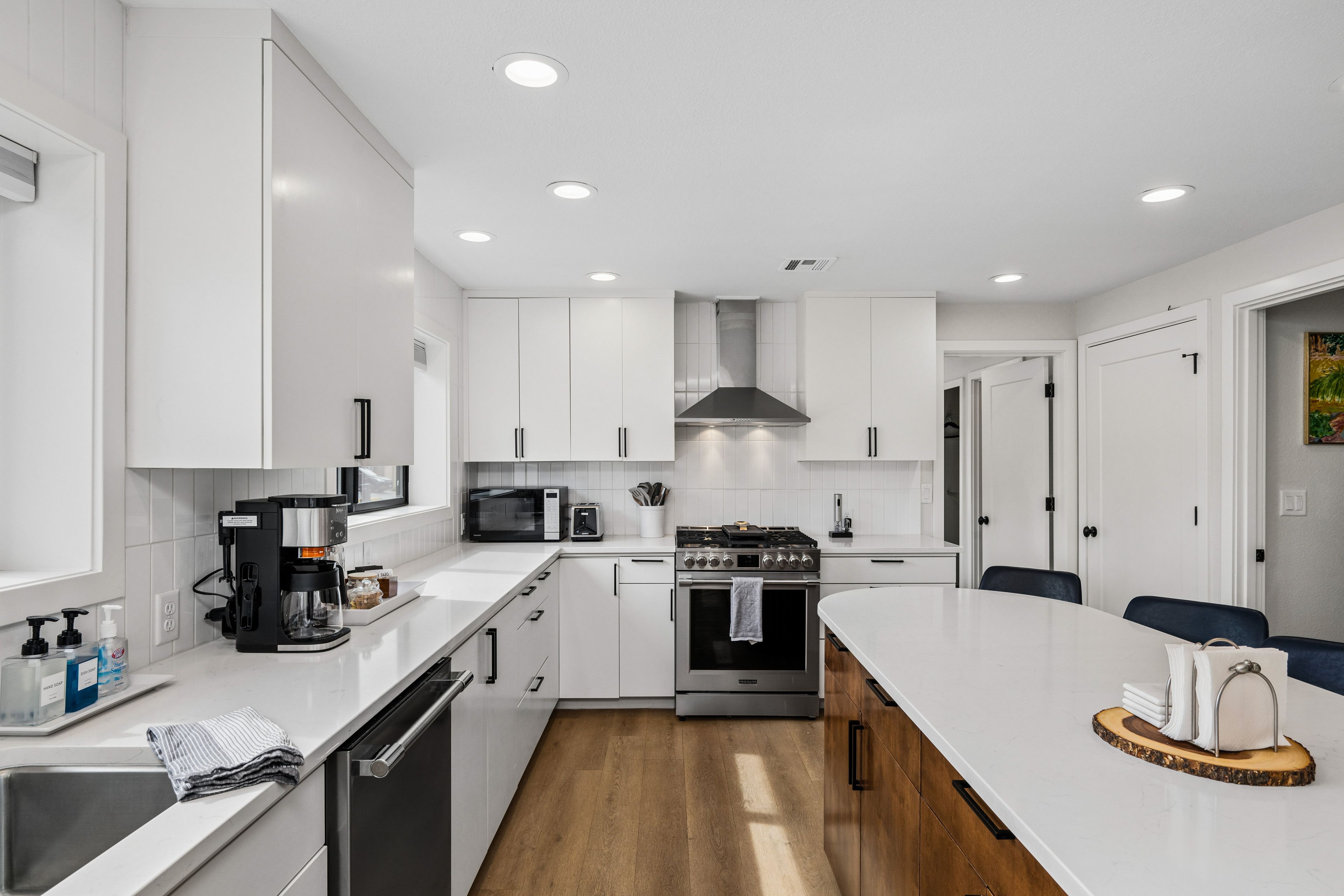 A modern kitchen with white cabinetry, a stainless steel stove, a microwave, and a coffee maker.