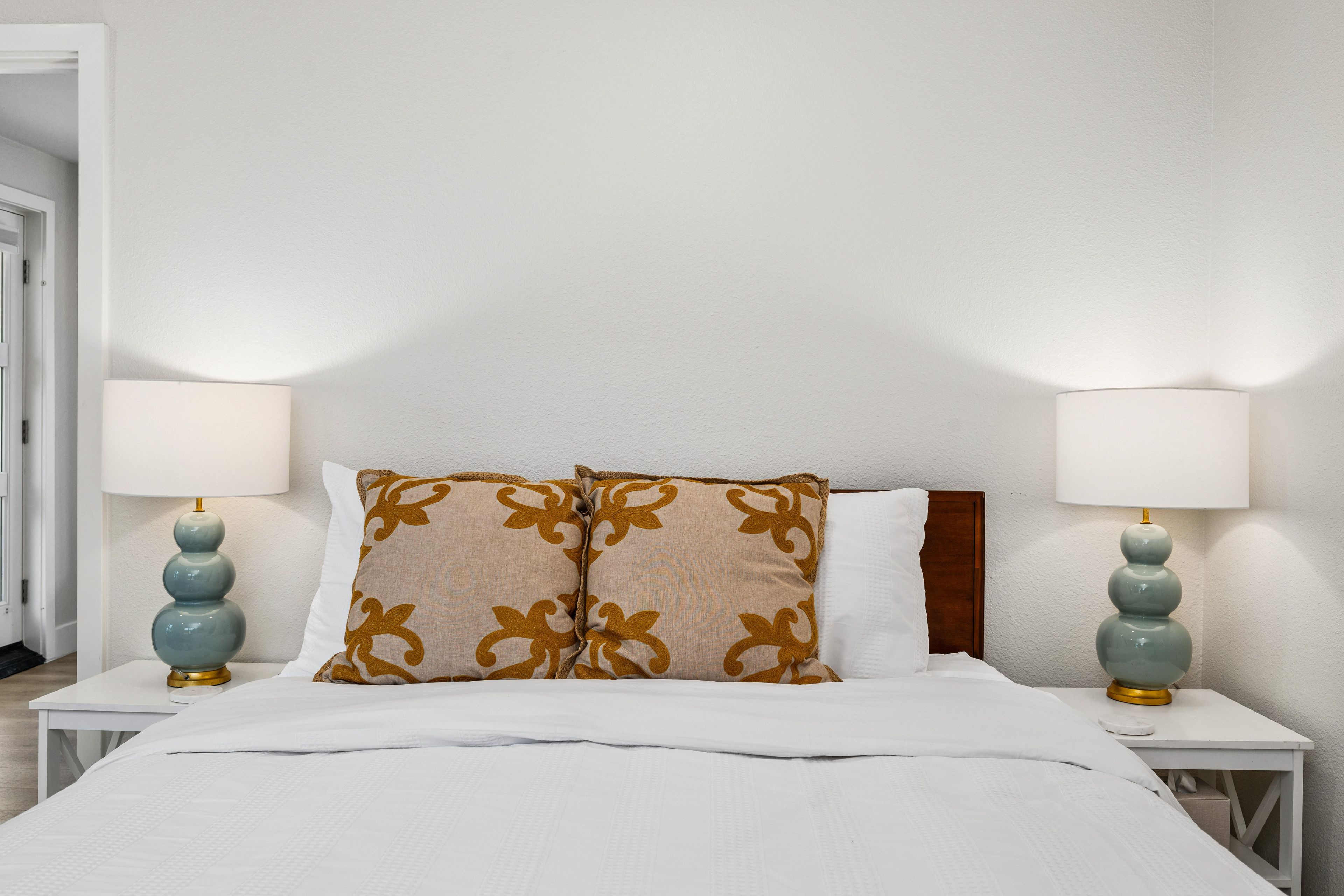 Une chambre d’hôtel avec un lit, deux tables de chevet et des lampes.