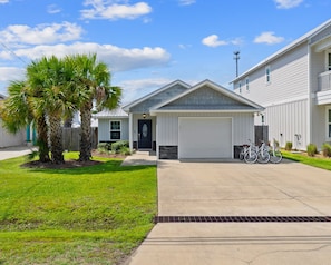 A residential building with a garage, a driveway, and a bicycle parked outside. - Private Pool Oasis on PCB West End | Short Walk to Beach | Bikes | Sleeps 8 (Panama City Beach)