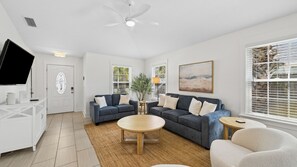 Ein modernes Wohnzimmer mit zwei Sofas, einem Couchtisch, einem Fernseher und einem Deckenventilator.