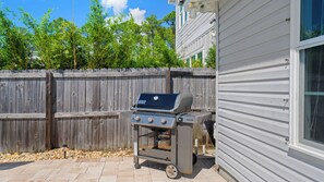 A barbecue grill with a digital display, positioned on a patio with a wooden fence and a house in the background. - Private Pool Oasis on PCB West End | Short Walk to Beach | Bikes | Sleeps 8 (Panama City Beach)