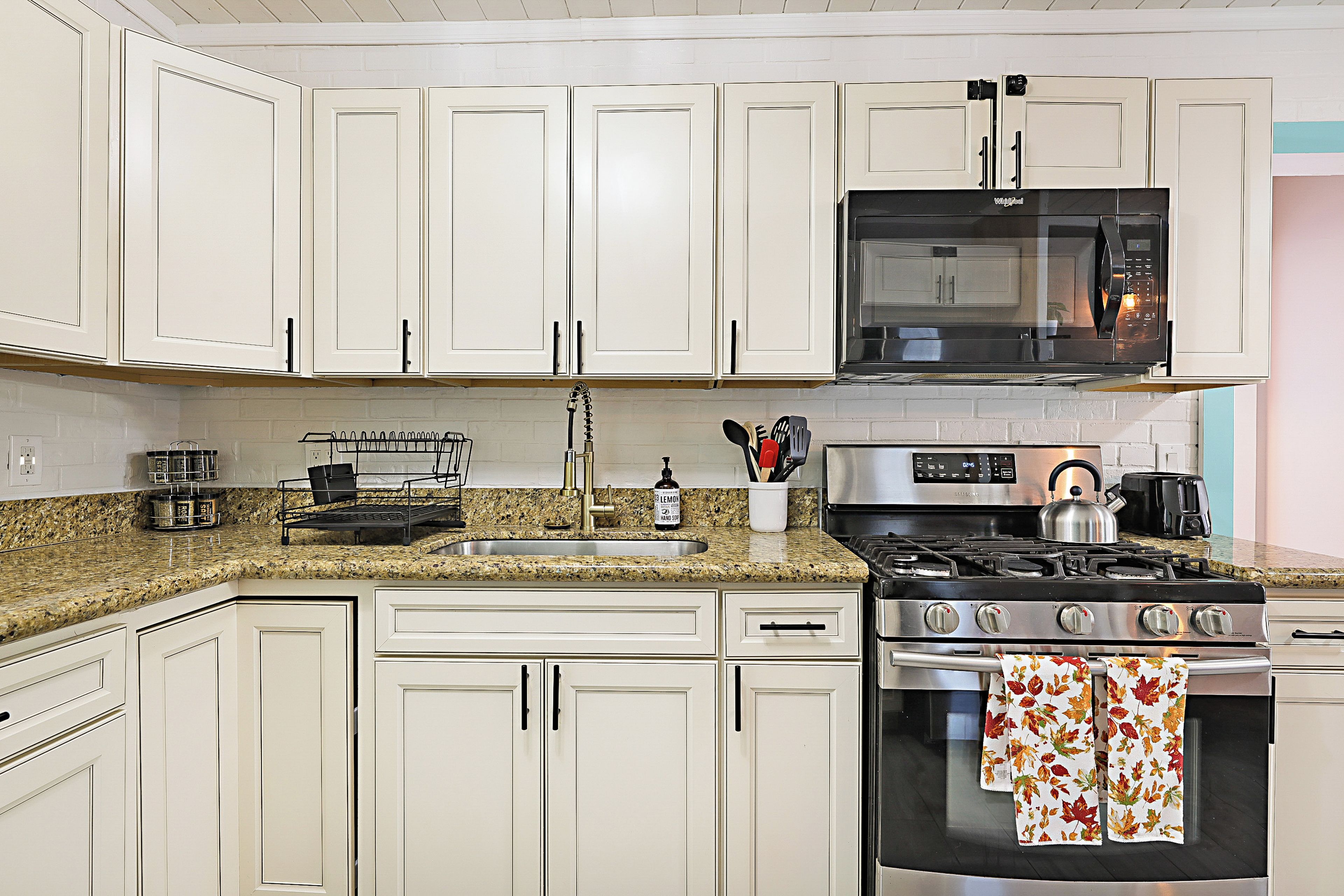 A kitchen with white cabinets, a stainless steel stove, a microwave, and a granite countertop.
