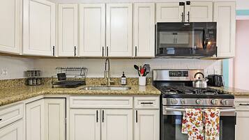 A kitchen with white cabinets, a stainless steel stove, a microwave, and a granite countertop.