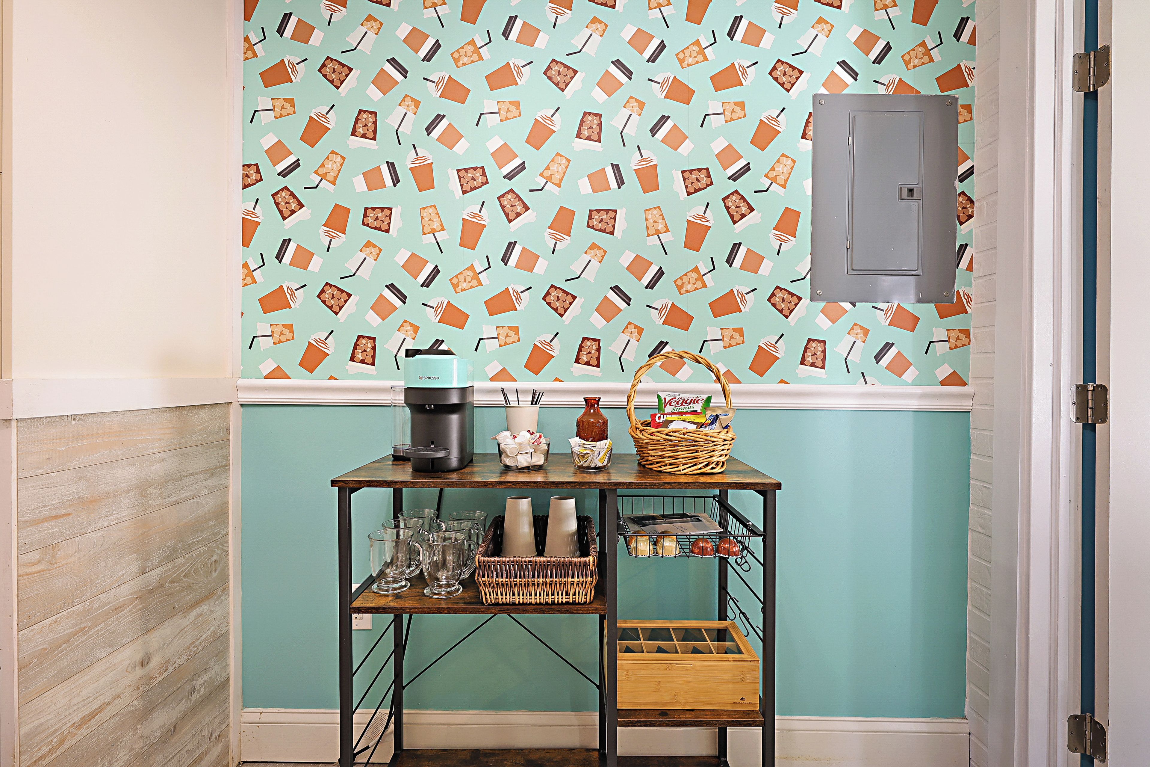 A kitchenette with a coffee maker, a basket of bread, and a shelf with glassware.