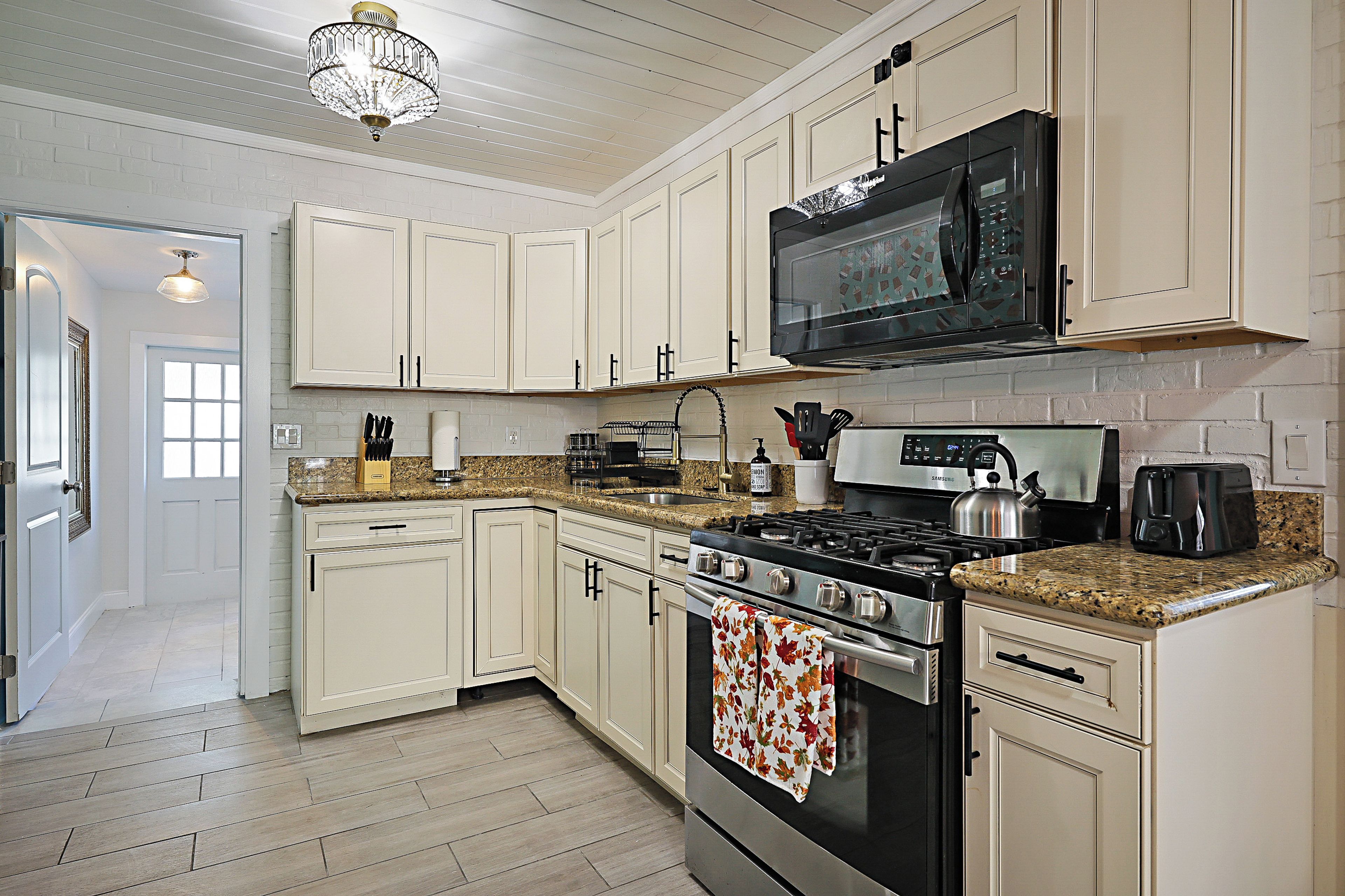 A kitchen with white cabinetry, a stainless steel range, a microwave, and a kettle.