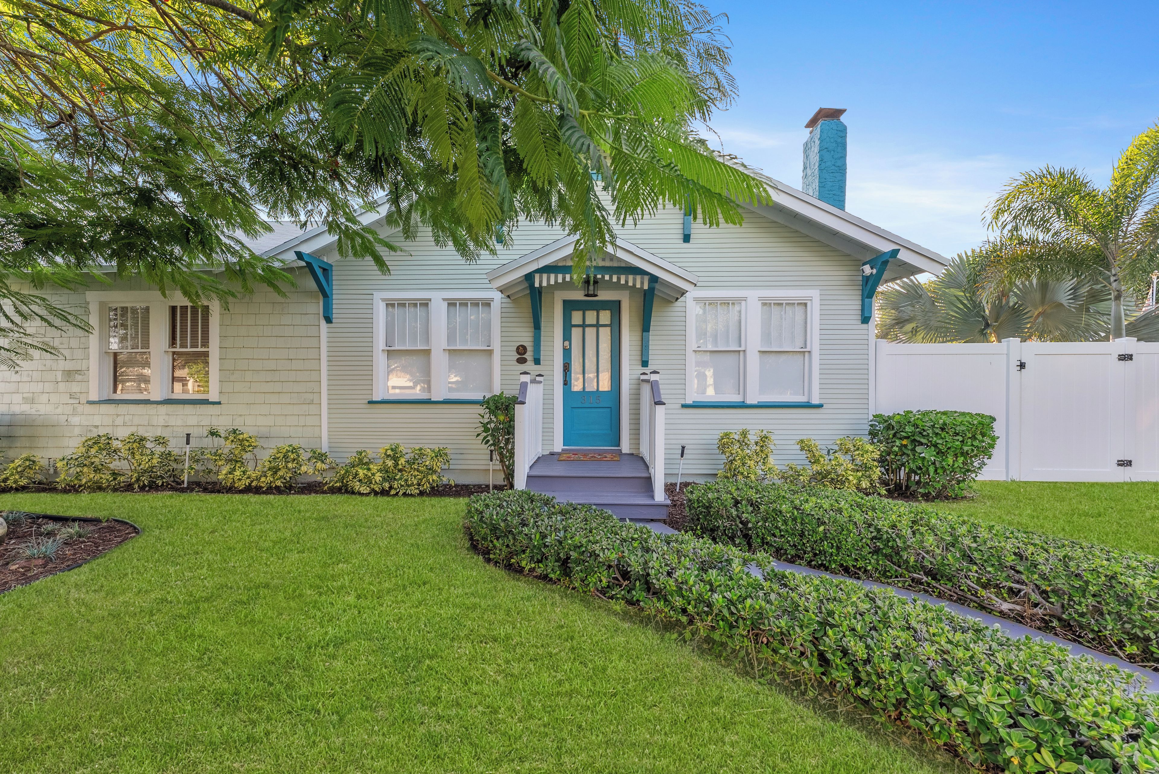 A single-story house with a front porch, a blue door, and a number 315 on the door.