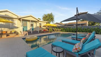 A pool area with lounge chairs, umbrellas, and a small pool.