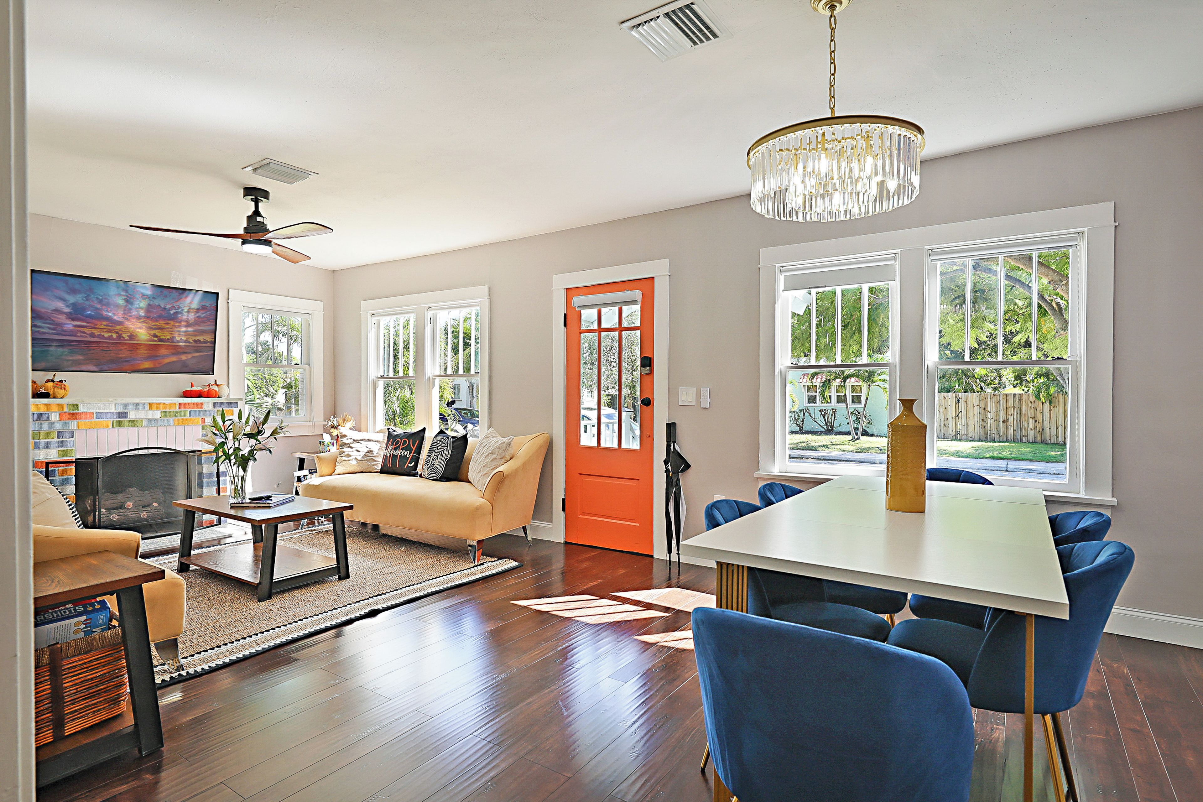 A spacious living room with a fireplace, a dining area, and large windows offering a view of the outdoors.