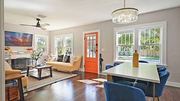 A spacious living room with a fireplace, a dining area, and large windows offering a view of the outdoors.