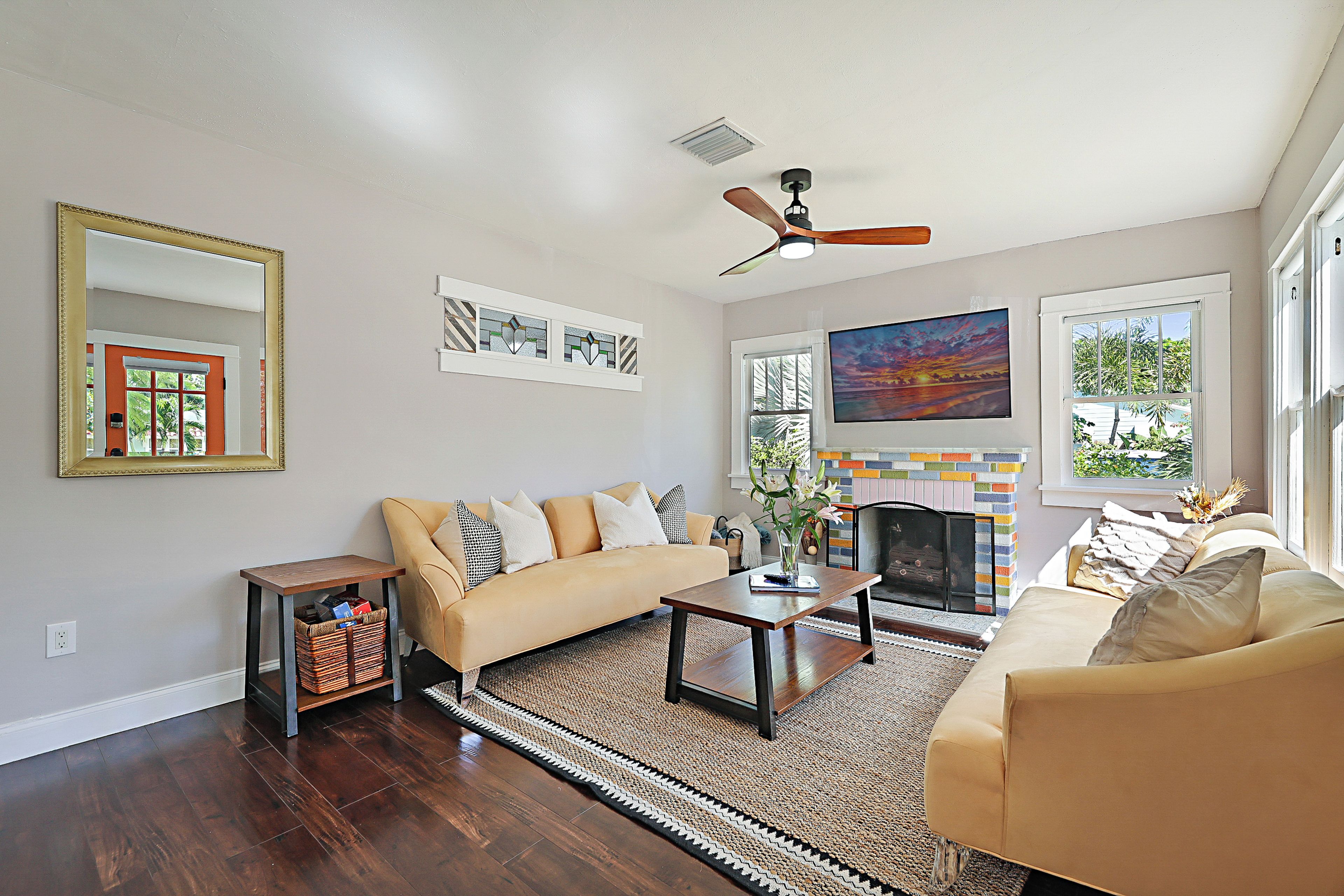 A living room with a sofa, a coffee table, a fireplace, and a ceiling fan.