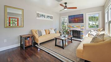 A living room with a sofa, a coffee table, a fireplace, and a ceiling fan.