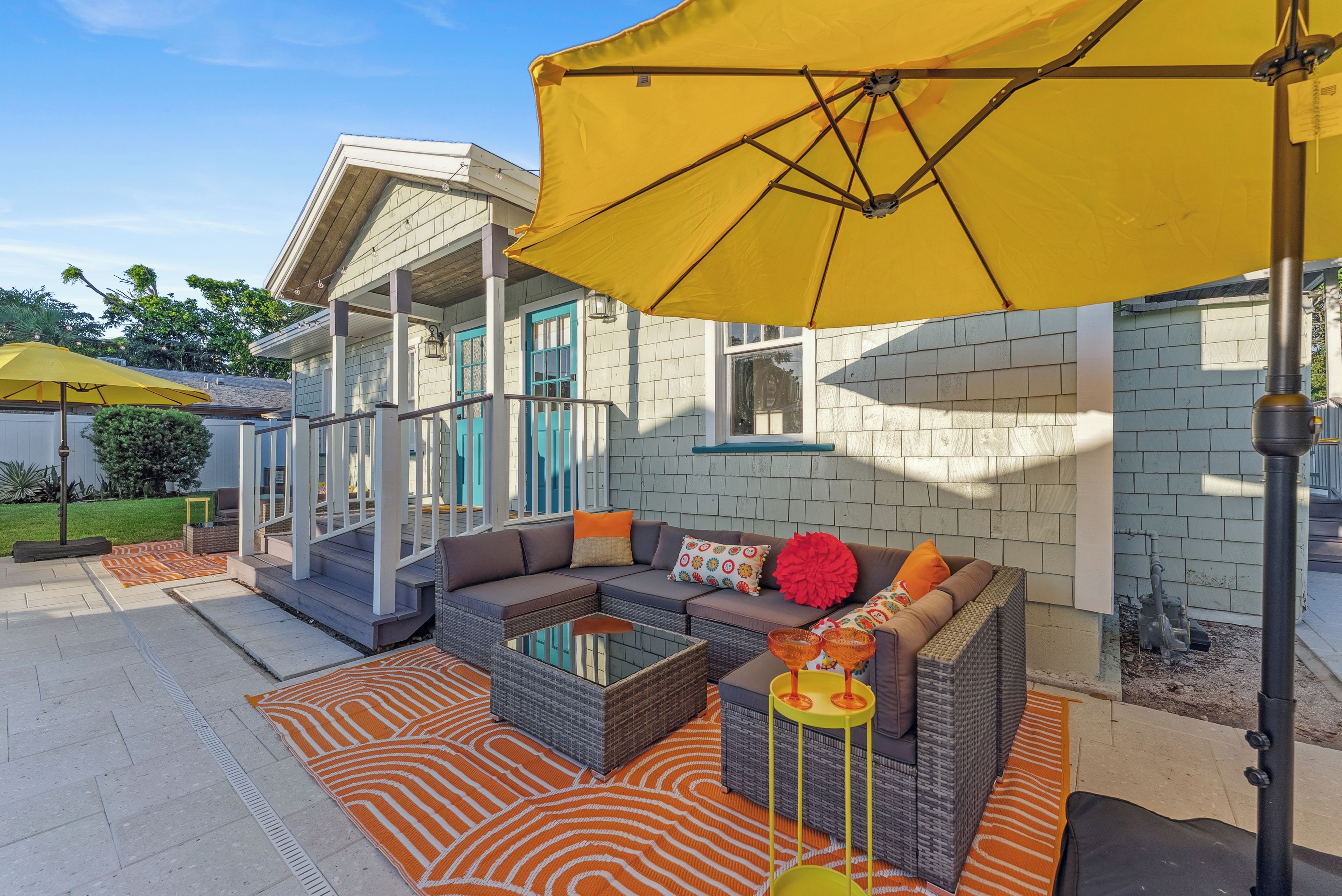 An outdoor seating area with a sofa, cushions, and a yellow umbrella.