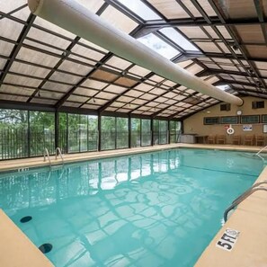 Ein Hallenbad mit Glasdach, klarem Wasser und einem Rettungsschwimmerstuhl.
