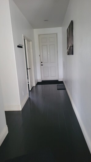 A hallway with a white door, a black mat at the entrance, and a black mat leading to the door. - Spacious 4-bedroom home in pleasant Moreno Valley ,nearby golf and lake nearby (Moreno Valley)