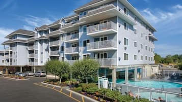 Um edifício residencial com vários andares, varandas, piscina e área de estacionamento.