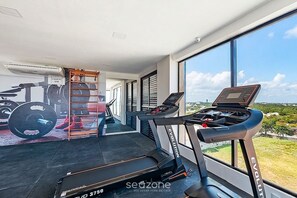 A modern home gym with exercise equipment, a treadmill, and a view of the outdoors. - Studio in Condo. w/ Pool & Sea View Clf0601 (Salvador)