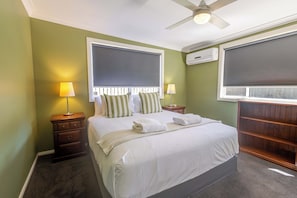 A bedroom with a bed, two bedside tables, a ceiling fan, and an air conditioning unit. - Summer Daze, Pool & Pet Friendly, Dubbo (Dubbo)