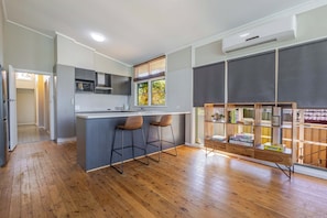 A modern kitchen with a central island, bar stools, and a built-in bookshelf. - Summer Daze, Pool & Pet Friendly, Dubbo (Dubbo)