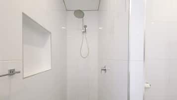 A modern shower with a glass enclosure, a visible drain, and a wall-mounted control panel.