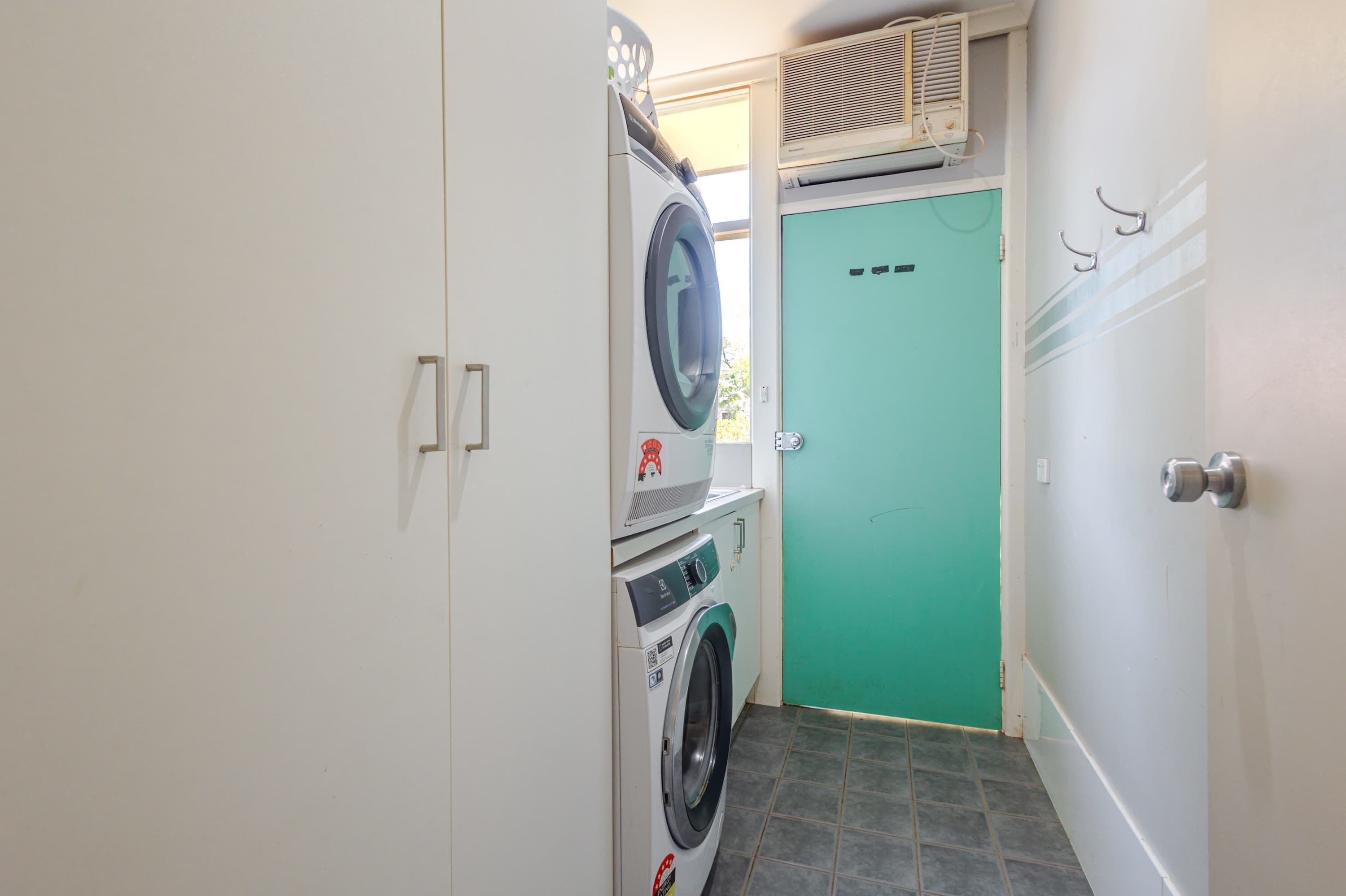 Een wasserette met een wasmachine, droger en gestapelde wasmanden.