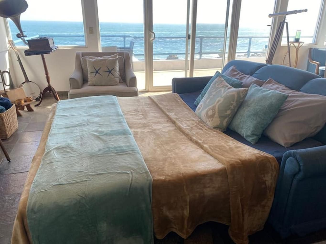A room with a bed, a sofa, and a view of the ocean.