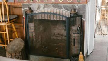 A stone fireplace with a glass door, a wooden chair, and a broom leaning against the wall.