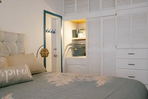 A bedroom with a bed, a wardrobe, and a laundry area.