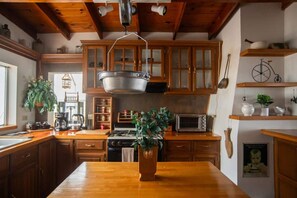 A kitchen with wooden cabinets, a hanging pot rack, a stove, and a coffee maker.