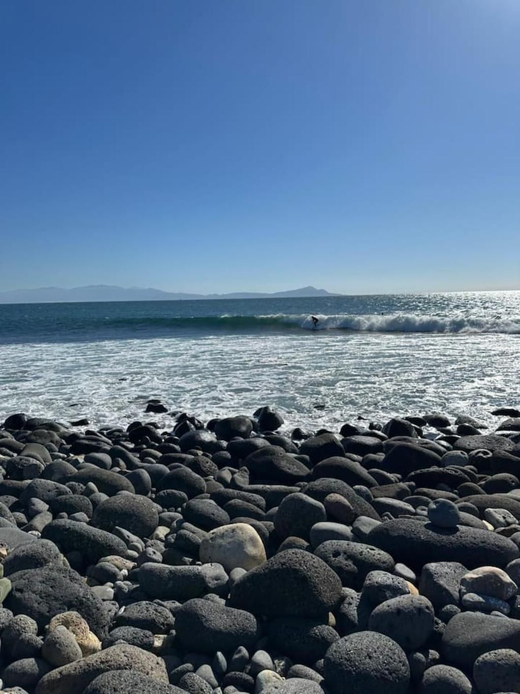 A rocky beach with waves and a clear sky.