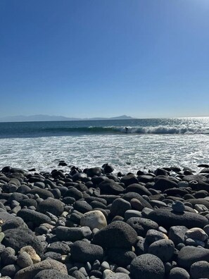 A rocky beach with waves and a clear sky.