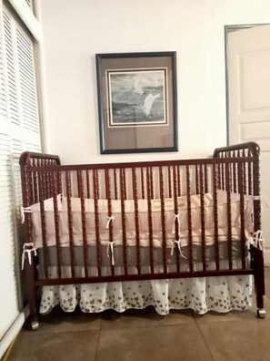 A wooden bench with a white and brown patterned cushion, a framed picture on the wall, and a white door in the background.