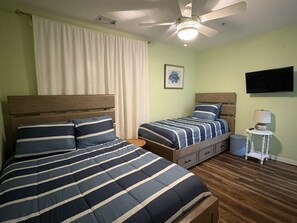 A hotel room with two beds, a ceiling fan, a television, and a small table with a lamp. -  2-bedroom beach condo steps from the beach with amazing sunsets (Virginia Beach)