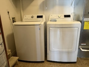 Dos lavadoras LG blancas de carga frontal en un cuarto de lavado con piso de baldosas y un armario metálico.