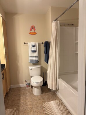 Een badkamer met een toilet, een douchegordijn en een handdoekhouder.